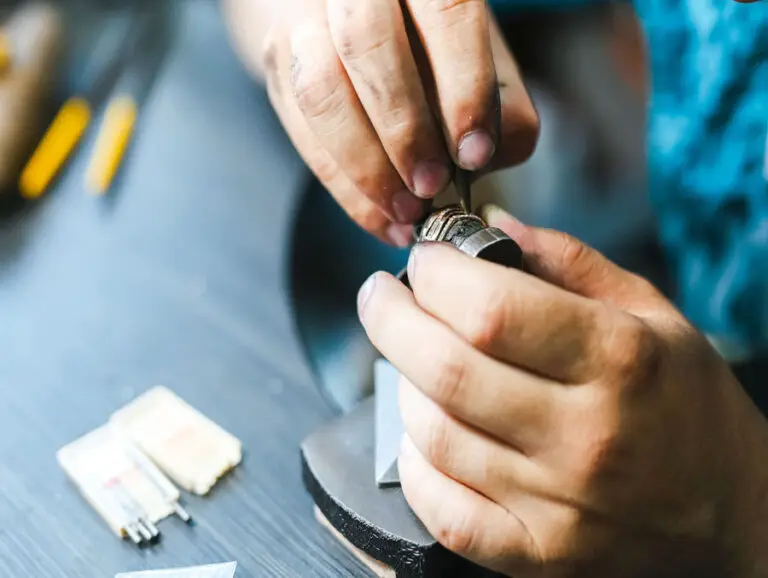 Sertisseur tenant une bague dans laquelle il sertit des diamants