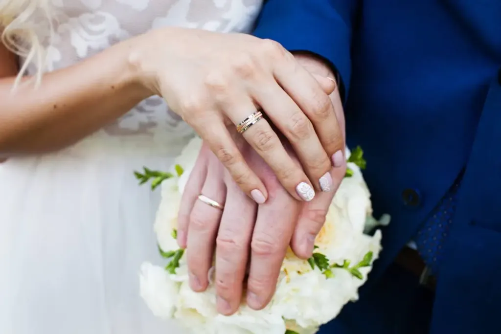 Un couple avec leurs alliances en or 18 carats portées au doigt