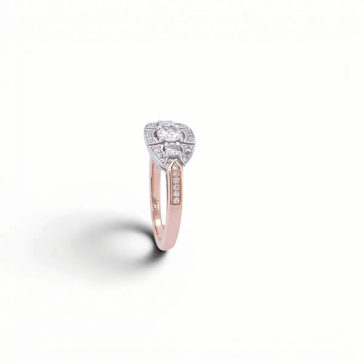 Bague ancienne bicolore or rose et or blanc, trois diamants en ligne dans un plateau géométrique, vue de trois-quarts
