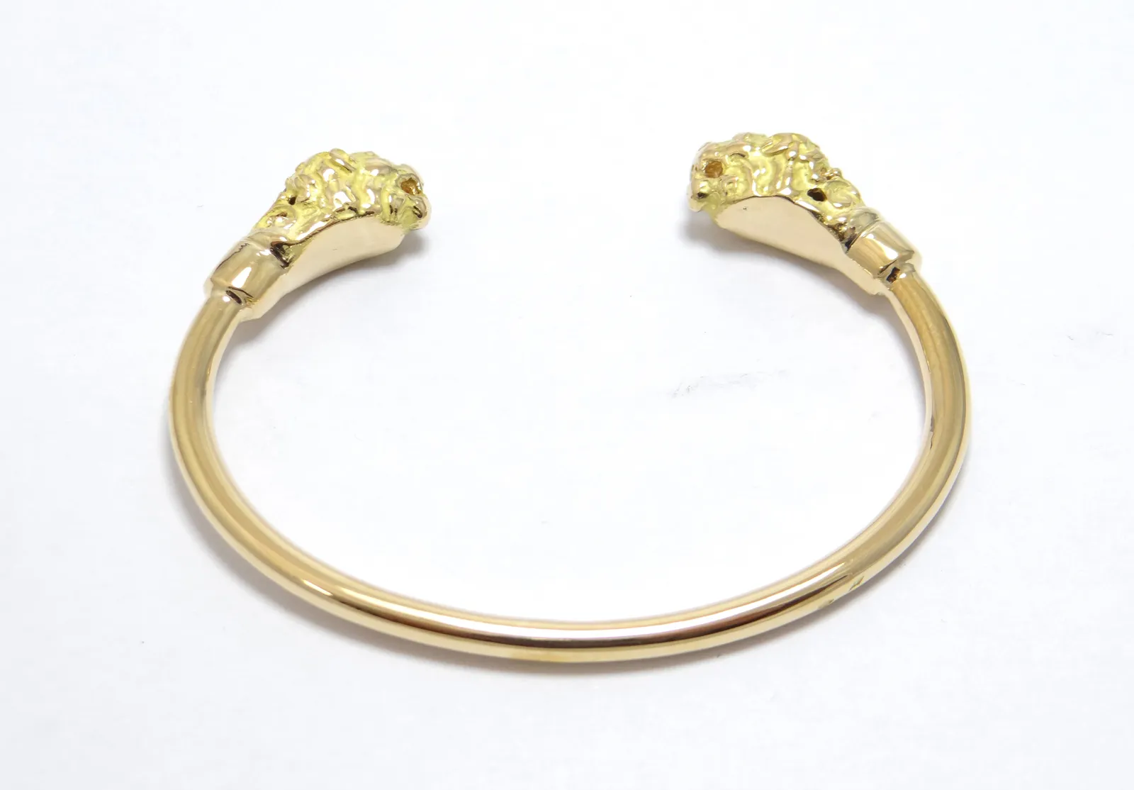 bracelet massif ouvert avec deux tetes de lions serti de diamants dans les yeus en or jaune 18 carats