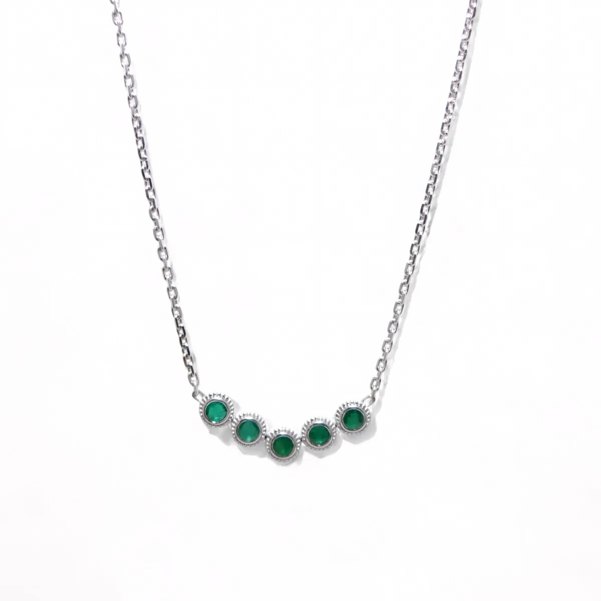 Collier en or blanc 18 carats serti de cinq émeraudes rondes naturelles en serti clos, bijou raffiné et élégant de haute joaillerie.