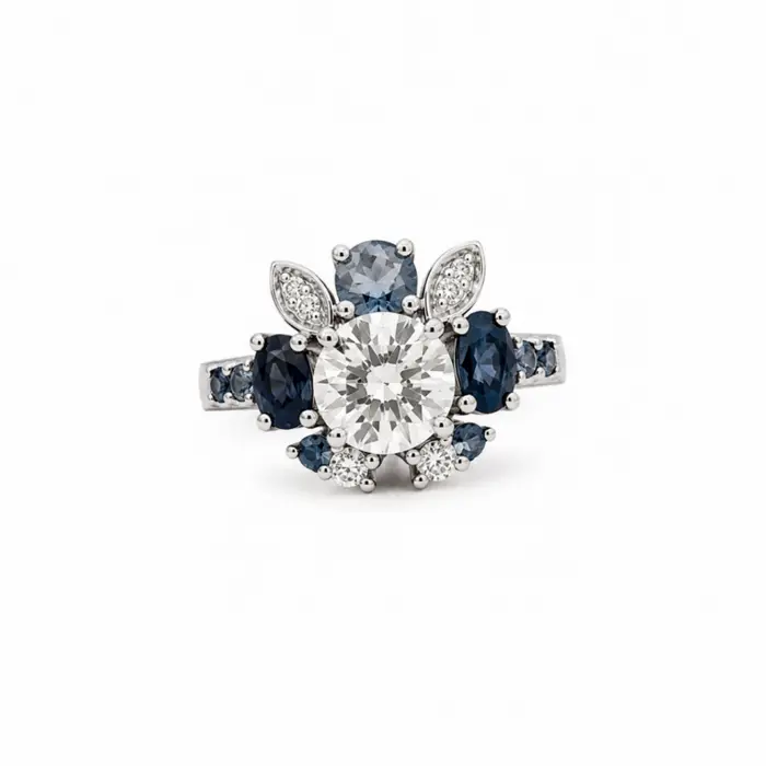 Bague fleur en or blanc 18 carats sertie de saphirs bleus et de diamants, création joaillière raffinée inspirée de la nature.