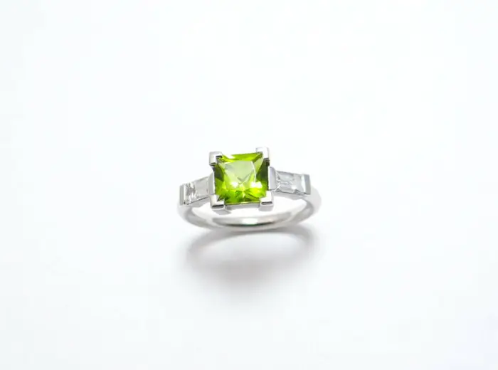 bague or peridot de forme carré au centre et deux diamants baguettes monture en or blanc paladié