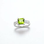 bague or peridot de forme carré au centre et deux diamants baguettes monture en or blanc paladié