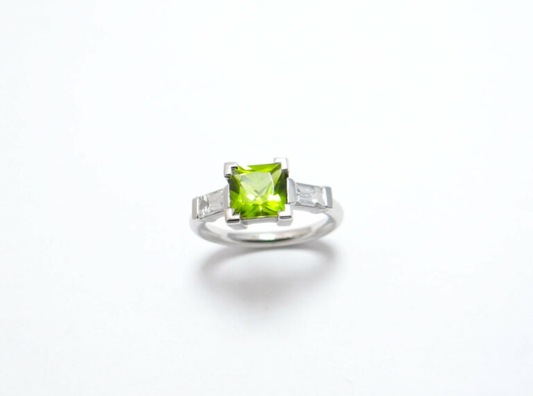 bague or peridot de forme carré au centre et deux diamants baguettes monture en or blanc paladié