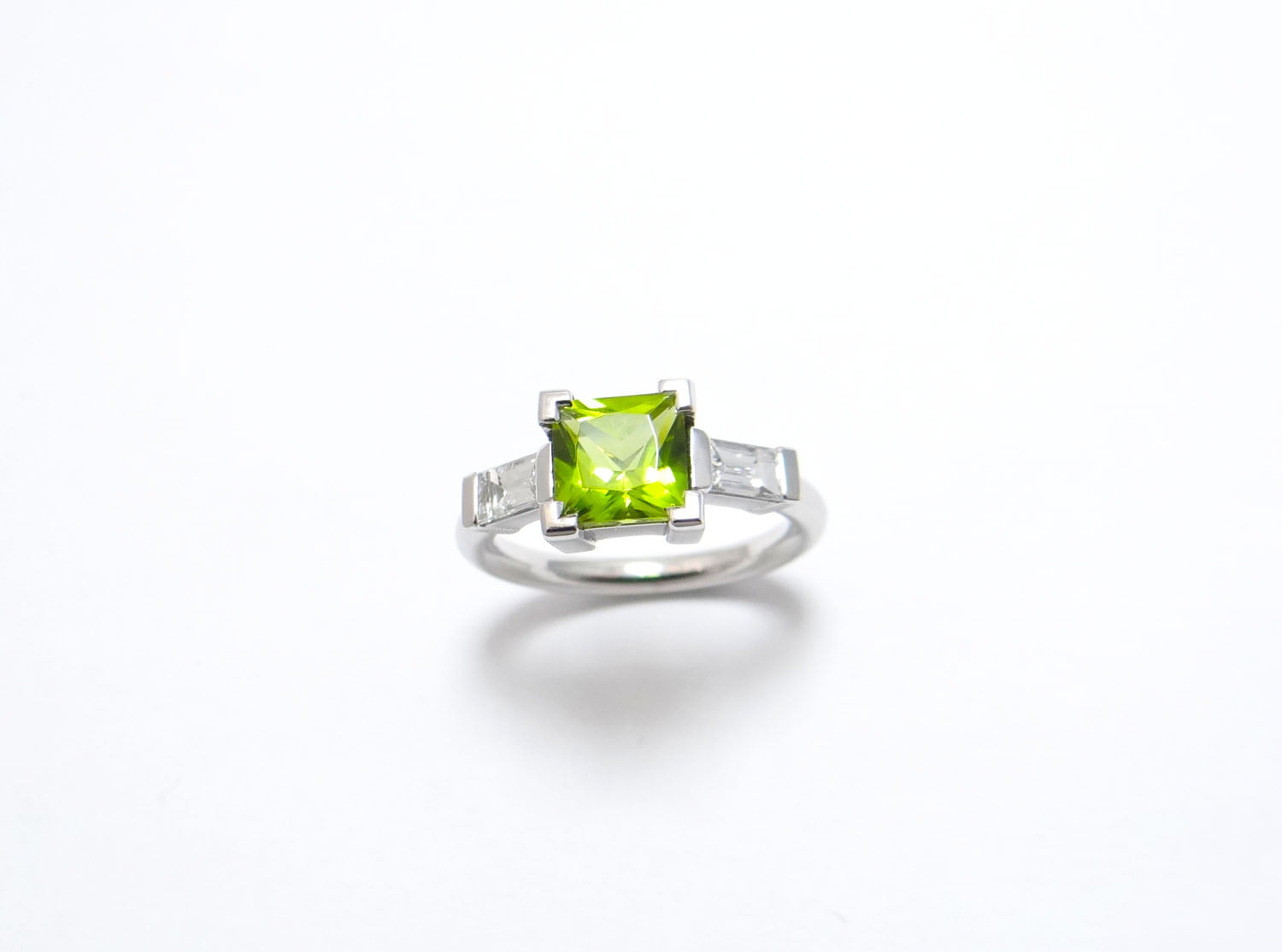 bague or peridot de forme carré au centre et deux diamants baguettes monture en or blanc paladié