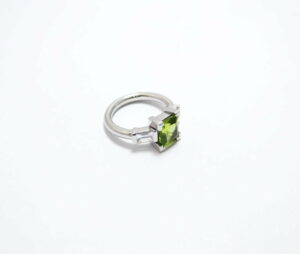 bague en or blanc palladié avec deux diamants baguettes en serti semi clos et un peridot en serti griffe de taille carré