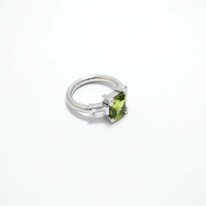 bague en or blanc palladié avec deux diamants baguettes en serti semi clos et un peridot en serti griffe de taille carré