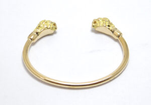 bracelet massif ouvert avec deux tetes de lions serti de diamants dans les yeus en or jaune 18 carats