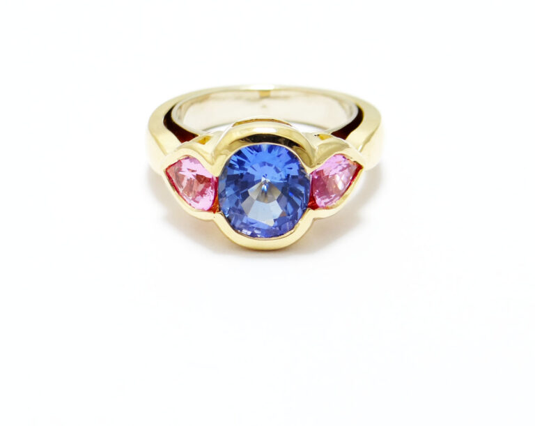 bague moderne avec une tanzanite au centre taille coussin de 3 carats et deux saphirs rose poire sur les cotés monture or jaune