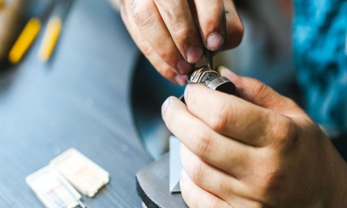 sertisseur tiend dans ses mains une bague dans laquelle il sertis des diamants